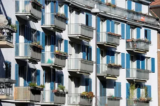 Wohnungen in Zürich, Häuserfassade mit Balkonen und blauen Fensterläden.