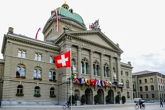 Bundeshaus in Bern, Schweiz, mit Landesfahne und Kantonsfahnen.