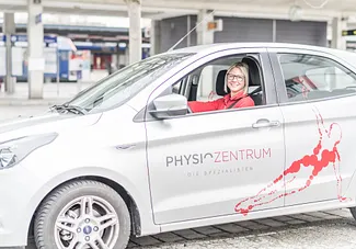Physiotherapeutin sitzt im Praxisauto