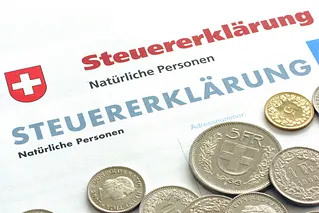 Vorderseite einer Schweizer Steuererklärung mit Bargeldmünzen