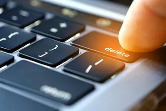 Finger drückt auf Delete-Taste einer Tastatur