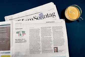 NZZ am Sonntag mit aufgeschlagenem Artikel «Geld & Geist» von Jürg Müller und ein Kaffee