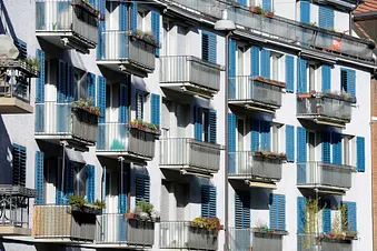 Wohnungen in Zürich, Häuserfassade mit Balkonen und blauen Fensterläden.