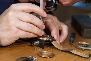 Hände eines Uhrmachers mit mechanischer Uhr