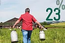 Bauer trägt zwei Milchkannen über ein Feld. Die Zahl 23 Prozent steht über dem Himmel.
