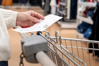 Mensch mit Kassenzettel in der Hand in einem Supermarkt